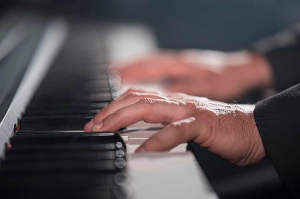 Close-up of hands pressing black and white keys on a piano keyboard.