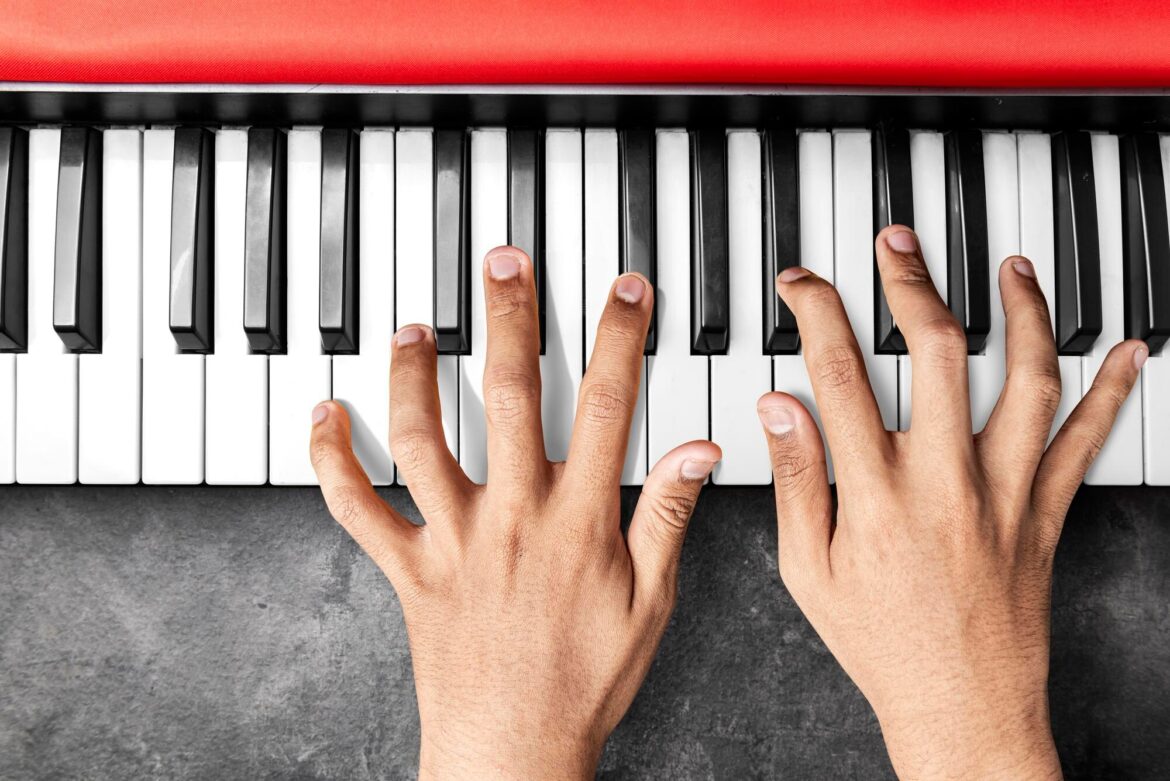 Inside a Music Scale: Steps, Patterns, and a Home Note Overhead close-up of two hands playing black and white piano keys.