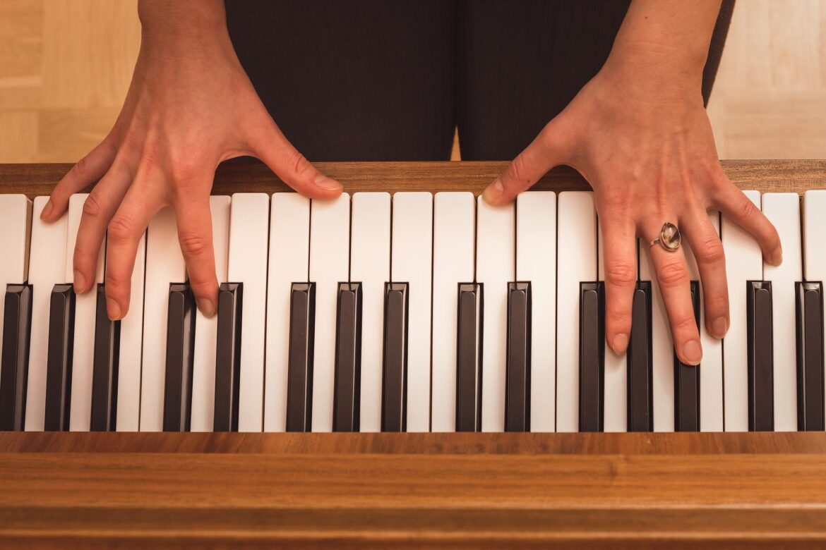 Overhead view of two hands playing an unmarked piano keyboard.