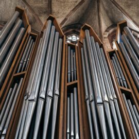 Tall ranks of metal organ pipes beneath Gothic arches in a Nuremberg cathedral.